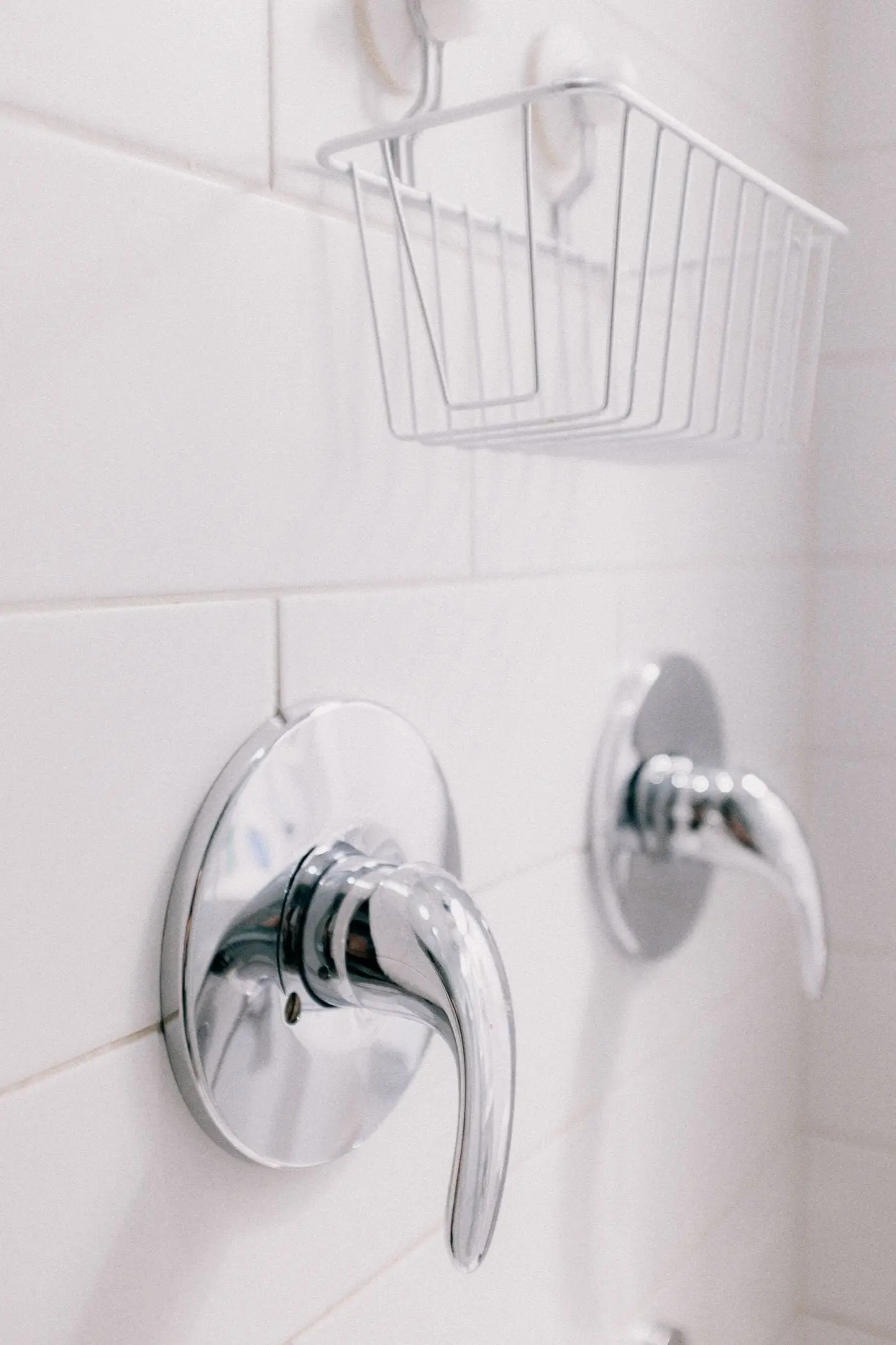 Clean chrome bathroom tapware against white tiling.
